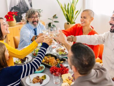 Happy multi generational family toasting white wine at home Thanksgiving party celebration