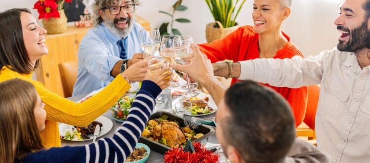 Happy multi generational family toasting white wine at home Thanksgiving party celebration